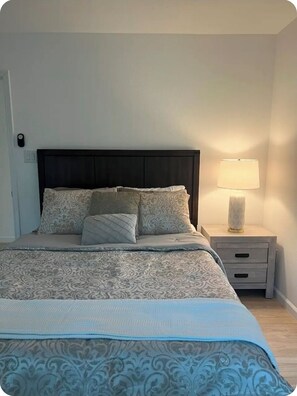 A neatly made bed with patterned bedding, a bedside lamp, and a nightstand with a drawer. - Fabulous 4-bedroom 2.5 bath Lake Cottage (Montgomery)