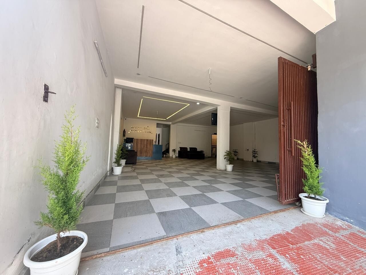 A hotel lobby with a checkered floor, potted plants, and a reception desk.