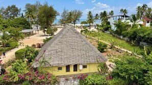 Una casa con techo de paja rodeada de exuberante vegetación y una playa.