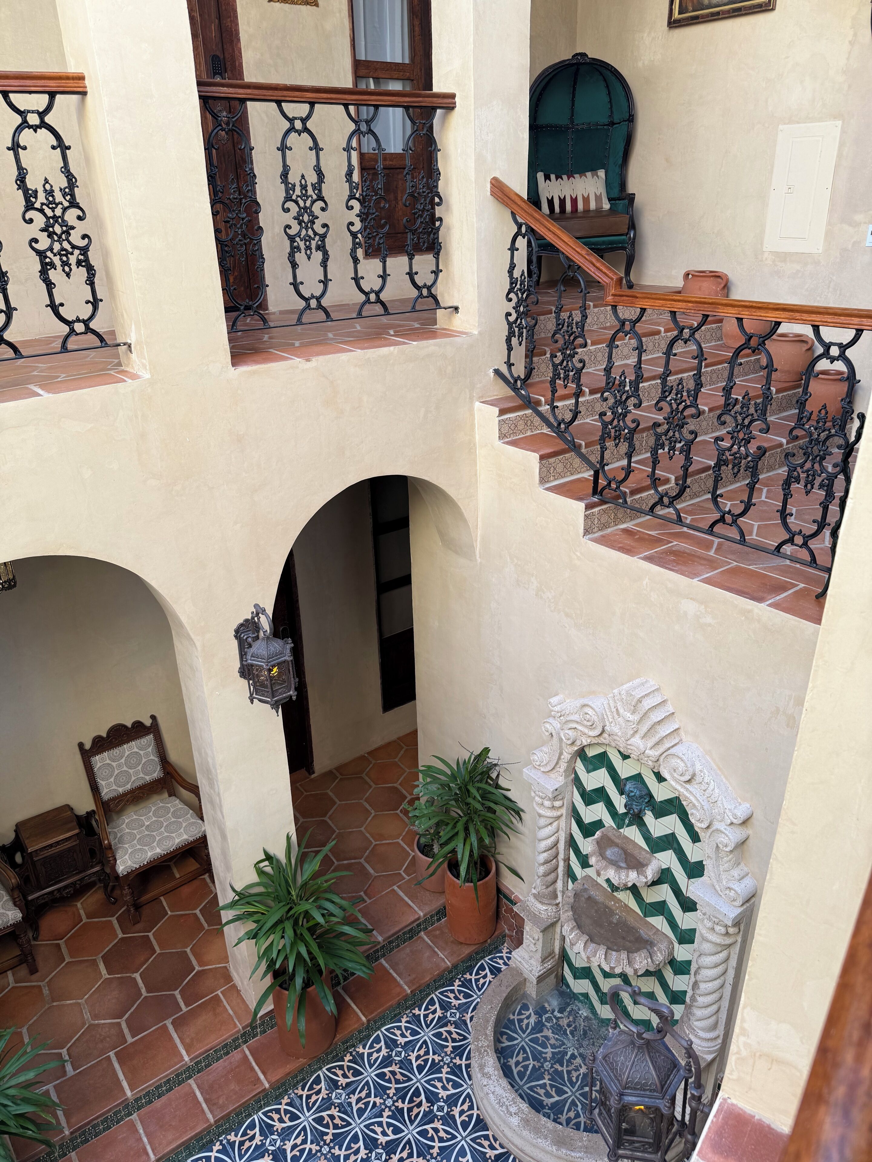 A multi-level interior with a staircase, a fountain, and potted plants.