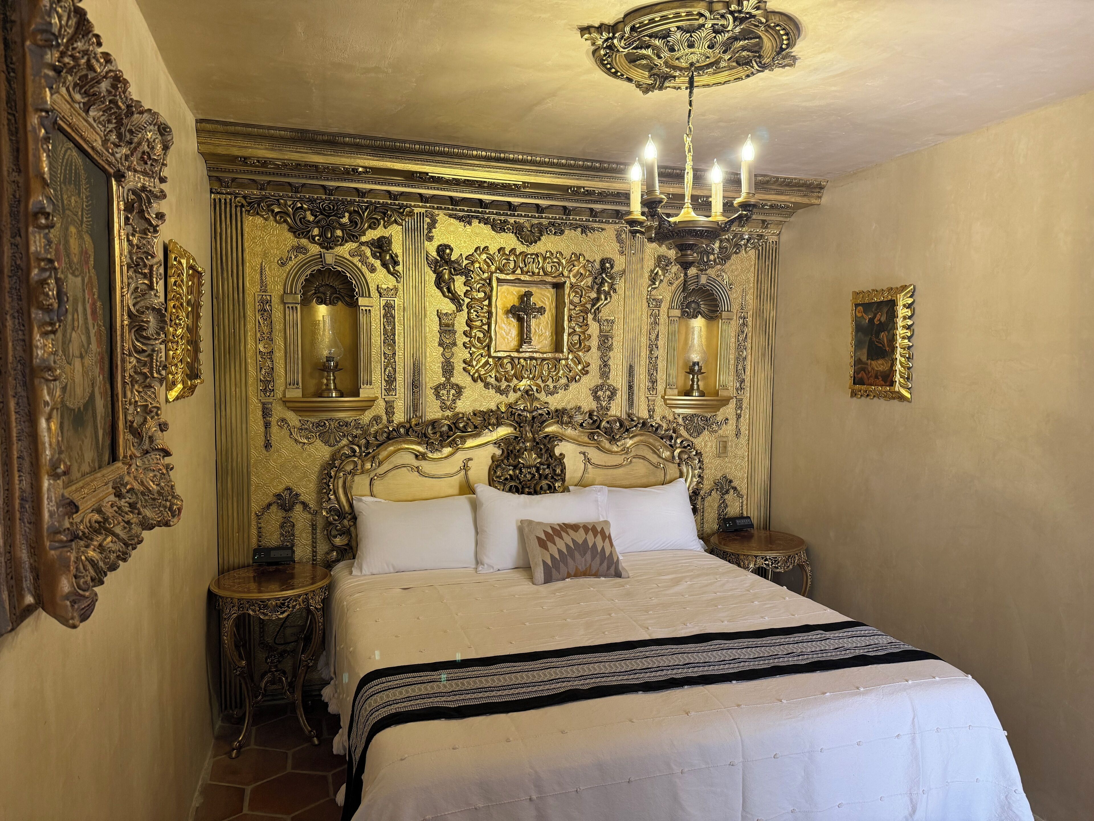 Una habitación ornamentada con una cama grande, paneles decorativos en las paredes y una araña.