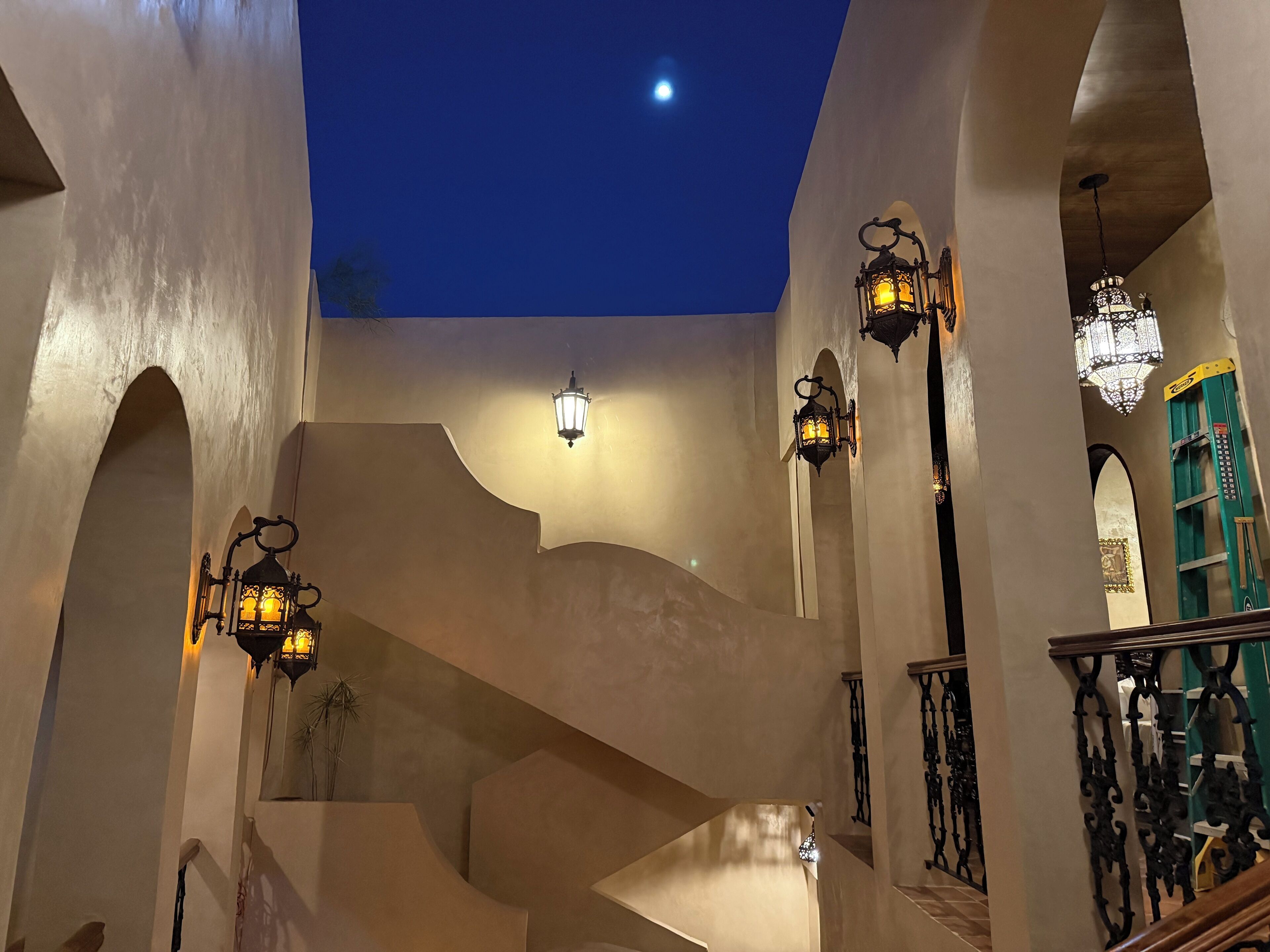 A staircase with ornate railings and wall-mounted lanterns, leading to a higher level.