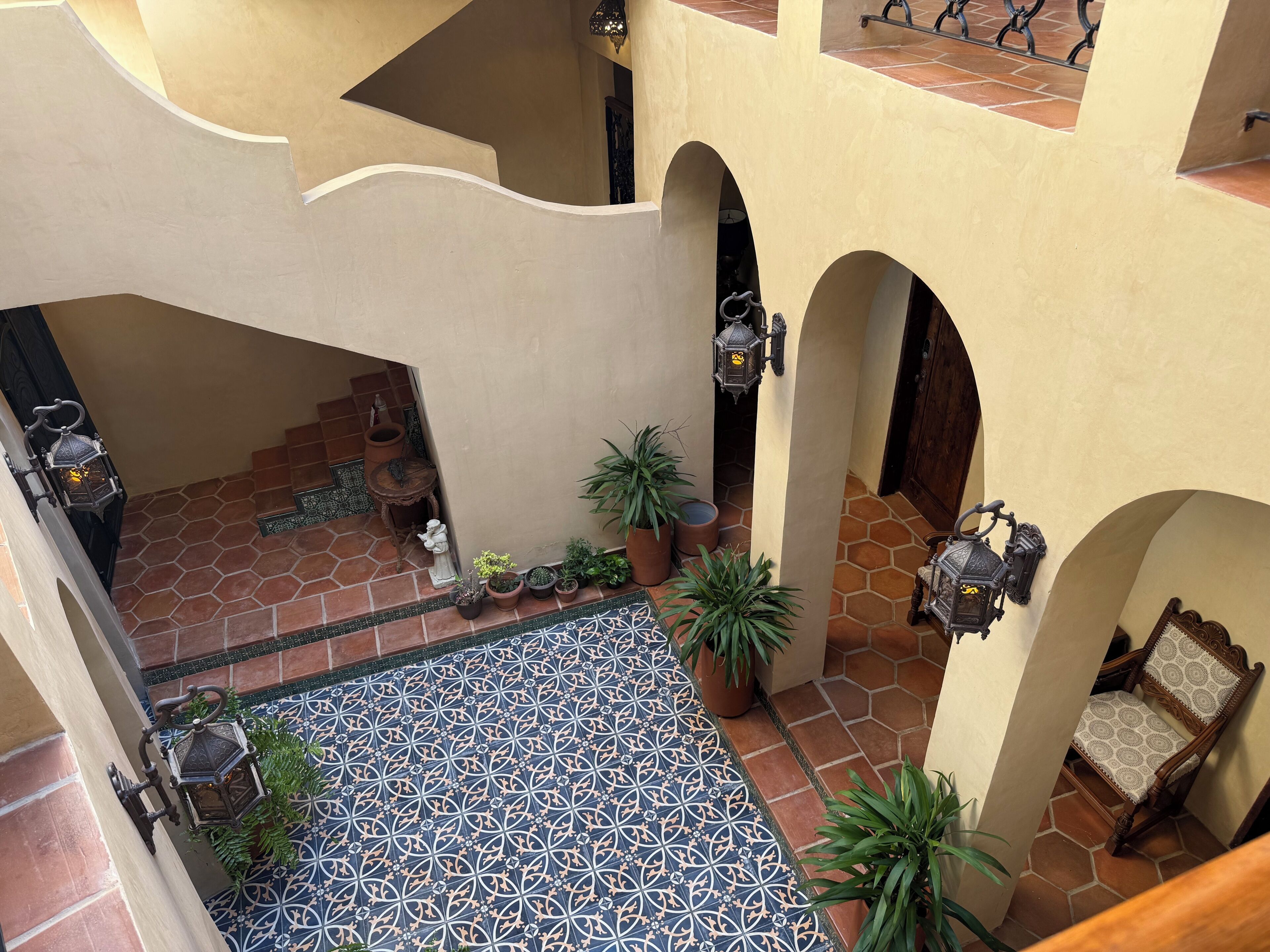 Une cour avec un sol carrelé, des plantes en pot et un escalier.