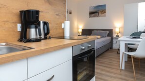 Ett modernt kök med en kaffebryggare, ugn och en matplats med ett bord och en stol.