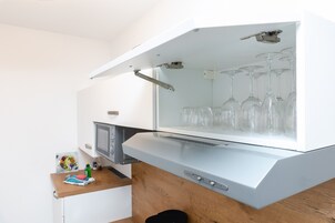 A kitchen with a built-in wine cooler containing several wine glasses.