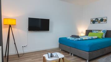 A modern bedroom with a bed, bedside table, lamp, TV, and artwork on the wall.