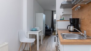 Una cucina compatta con lavello, piano cottura e macchina da caffè. C'è un'area pranzo con tavolo e sedie.