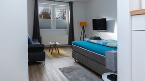 Una camera da letto moderna con un letto, una scrivania e una TV.