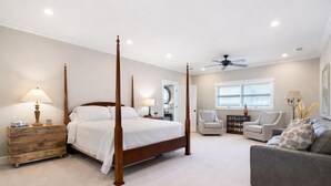 A four-poster bed, a ceiling fan, a grey sofa, and a wooden nightstand with a lamp. - Spacious 4 Bedroom Allatoona Lake House Perfect for a Comfortable Getaway (White)