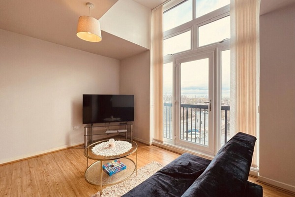 Floor-to-ceiling windows flood the living room with light and a sweeping city view beyond the balcony.