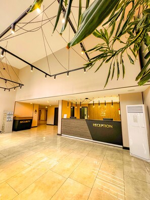 Zona de recepción de hotel con mostrador de recepción, mesa de seguridad y señalización para la recepción.