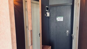 En hall med en garderob i trä, en grå dörr och en liten bänk.