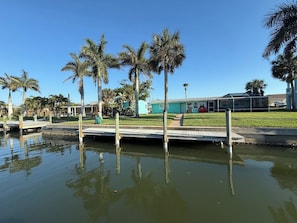 A waterfront property with a dock, palm trees, and a building with a green roof. - NEW POOL+ 3 Bedroom + No Bridge Gulf Access + Dock (Englewood)
