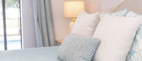 A bed with a light blue bedspread and two pillows, one with a textured pattern and the other plain.