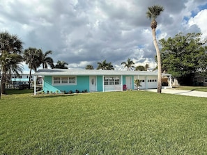 A single-story house with a front porch, a small garden, and a palm tree. - NEW POOL+ 3 Bedroom + No Bridge Gulf Access + Dock (Englewood)