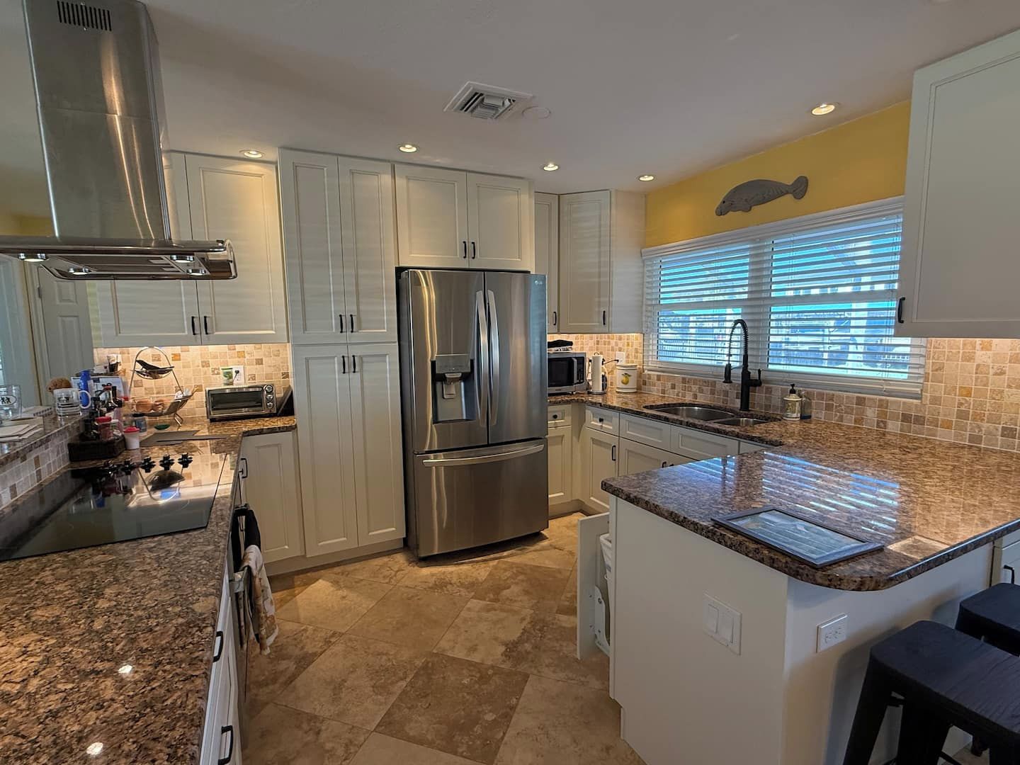 A modern kitchen with stainless steel appliances, white cabinetry, and a granite countertop.