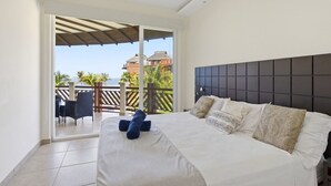 Une chambre à coucher avec un lit, des oreillers, une vue sur l’extérieur et un balcon.