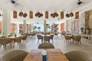 A spacious outdoor dining area with wicker furniture, ceiling fans, and a view of the ocean. - 434 - Two Bedroom Ocean View (Bajos de Chila)