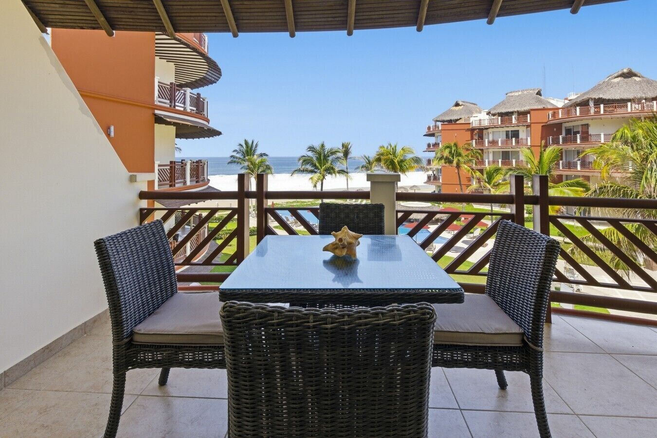 Ein Balkon mit Korbmöbeln, einem Tisch und einem dekorativen Gegenstand.