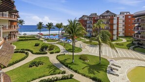 Un resort con piscina, palme e vista sull'oceano.