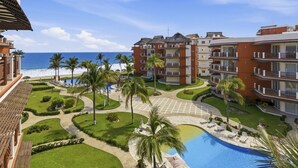 A resort with a pool, palm trees, and a view of the ocean.