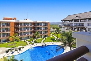 A hotel with multiple balconies, a swimming pool, and a view of the mountains.