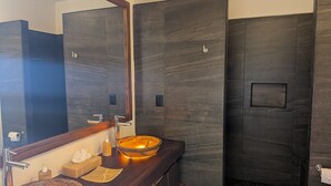 Ein modernes Badezimmer mit zwei großen, ovalen Waschbecken, einem großen Spiegel und dunkelholzverkleideten Wänden.