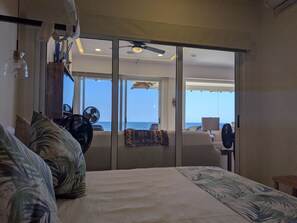 A hotel room with a bed, a ceiling fan, a view of the ocean, and a sliding door leading to a balcony. - 1412  Ocean Front 2 bedroom (Bajos de Chila)
