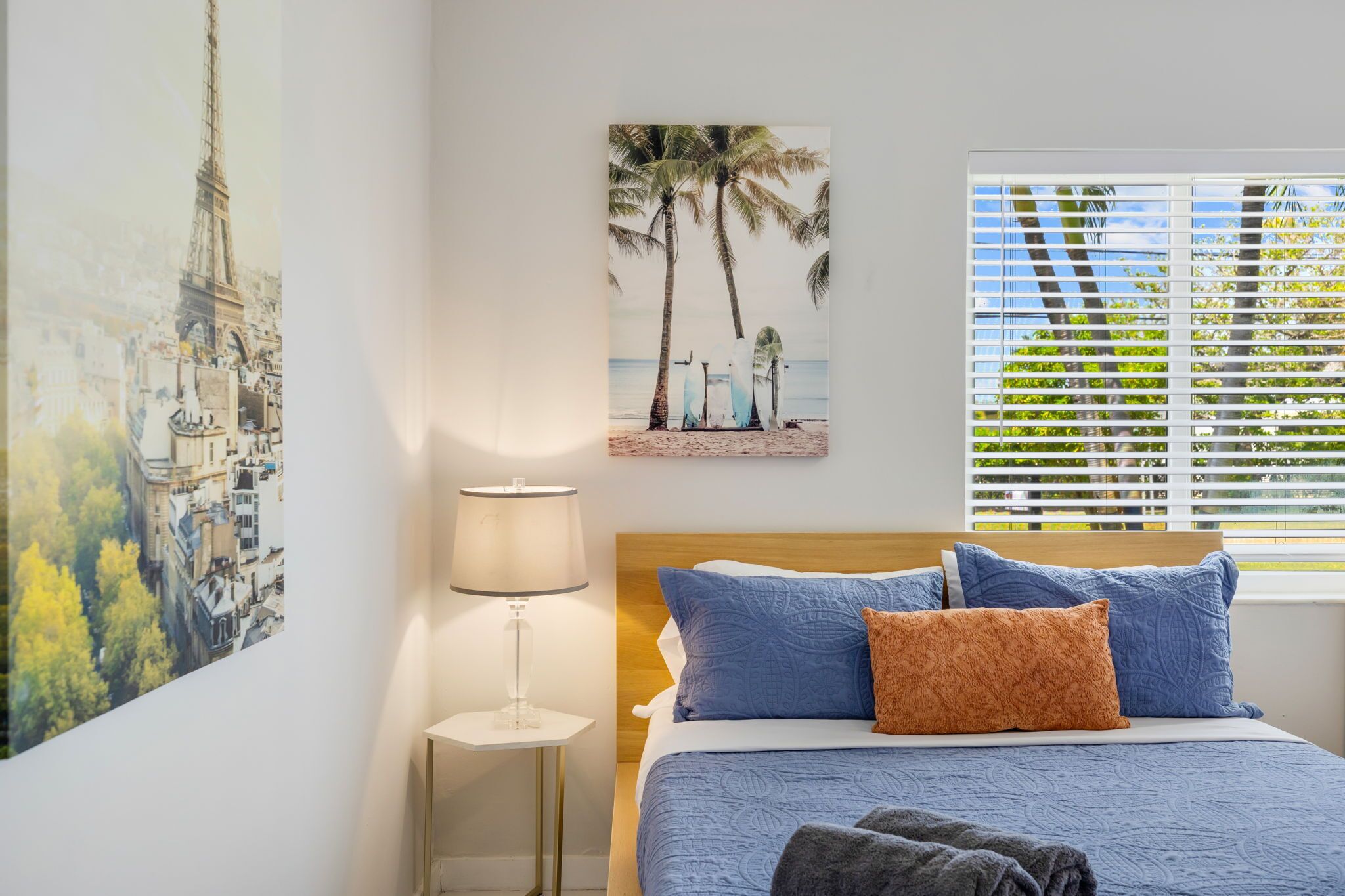 A bedroom with a bed, a nightstand, a lamp, and two wall art pieces.