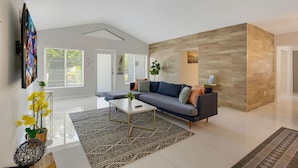 Ein modernes Wohnzimmer mit einem Ecksofa, einem Couchtisch und einem gemusterten Teppich.