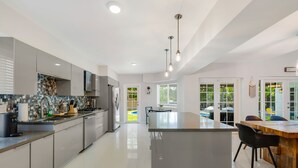 Eine moderne Küche mit einer zentralen Kochinsel, grauen Schränken und einem Essbereich mit einem Holztisch und Stühlen.