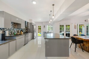 Eine moderne Küche mit einer zentralen Kochinsel, grauen Schränken und einem Essbereich mit einem Holztisch und Stühlen.