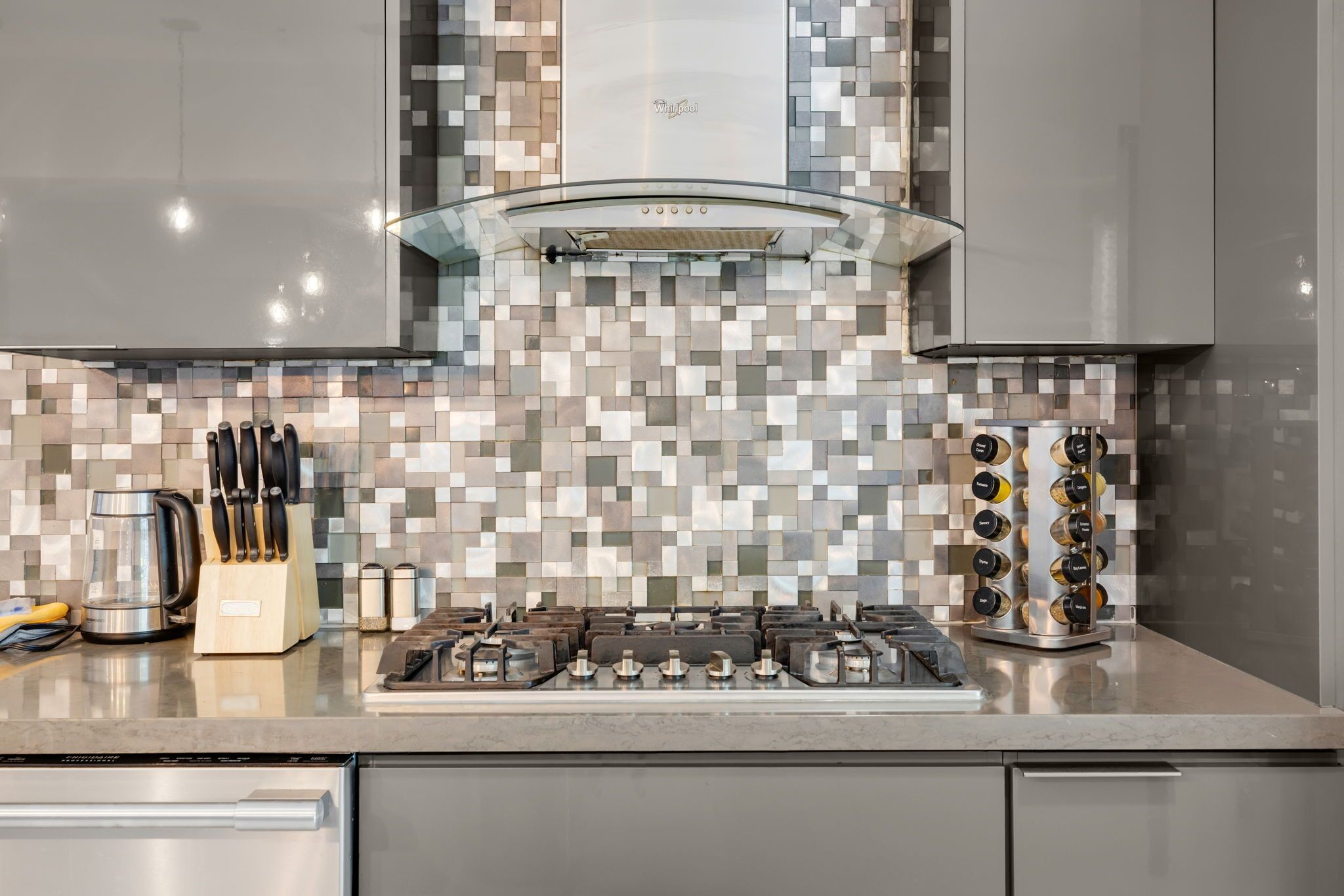 A modern kitchen with a tiled backsplash, stainless steel appliances, and a gas stove.