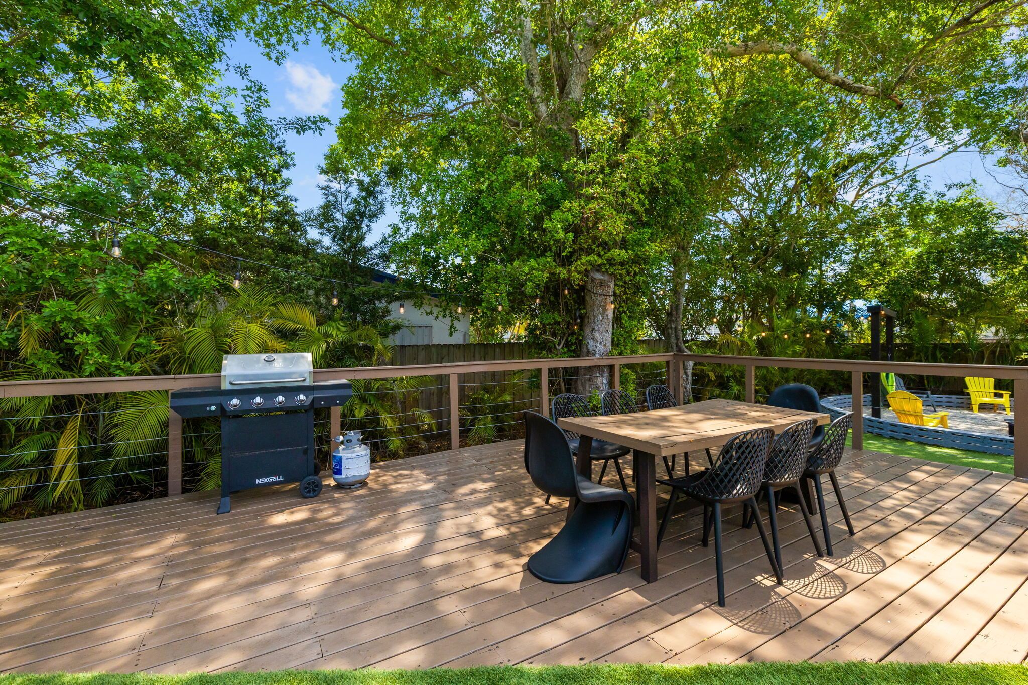 A deck with a grill, chairs, and a table.