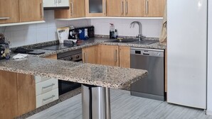 Eine moderne Küche mit Holzschränken, einer Granitabdeckung, Edelstahlgeräten und einem eingebauten Geschirrspüler.