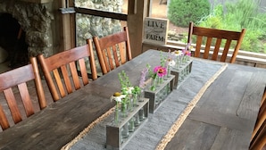 A rustic wooden dining table with a woven placemat, surrounded by wooden chairs.