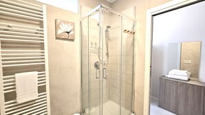 A modern bathroom with a glass-enclosed shower, a towel rack, and a vanity with a mirror. - Courtyard & Balconies (Como)