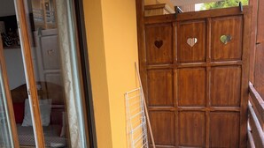 A room with a sliding glass door leading to a balcony, a wooden gate with heart-shaped cutouts, and a metal drying rack. - 4/5-person apartment at the foot of the slopes (Risoul)