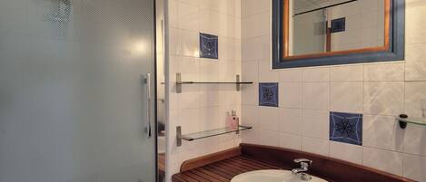 A modern bathroom with a glass shower enclosure, a wooden vanity, and a large mirror with a wooden frame.