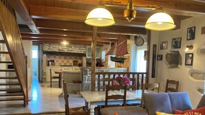 A spacious living area with a wooden staircase, a dining table with chairs, and a cozy seating area with cushions.