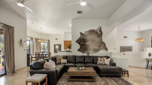 Un salon moderne avec un canapé d’angle, une table basse et une grande œuvre d’art accrochée au mur.