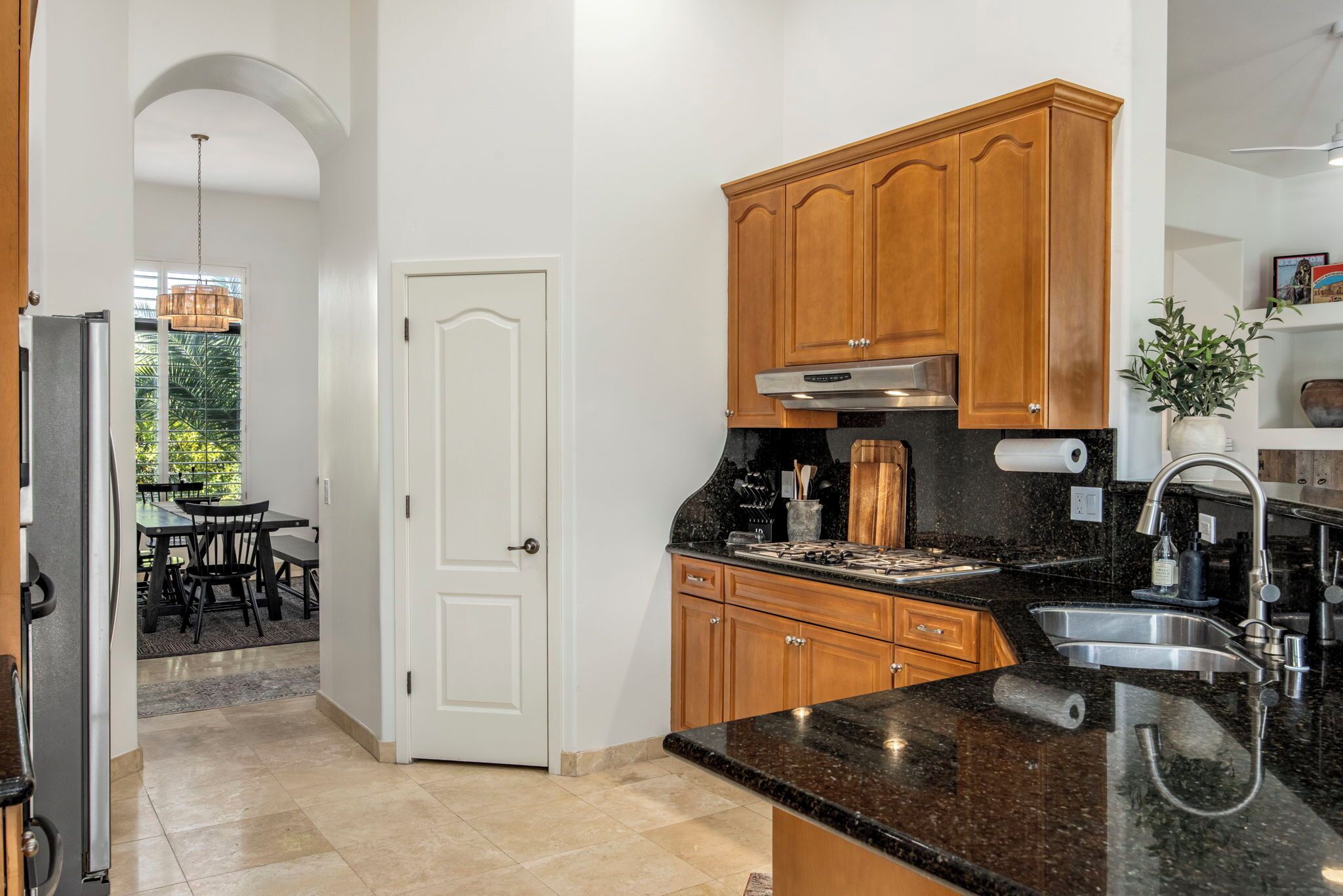 A kitchen with wooden cabinets, a black countertop, and a stainless steel sink.