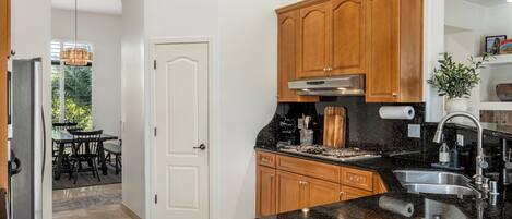 A kitchen with wooden cabinets, a black countertop, and a stainless steel sink.