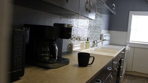 Een keuken met een koffiezetapparaat, een mok en een raam.