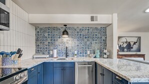 A modern kitchen with blue cabinets, a stainless steel dishwasher, and a patterned backsplash. - Walk to Shops Restaurants Coffee Live Music (Cave Creek)