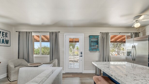 A modern kitchen with a marble countertop, a stainless steel refrigerator, and a dining area with a bench. - Walk to Shops Restaurants Coffee Live Music (Cave Creek)