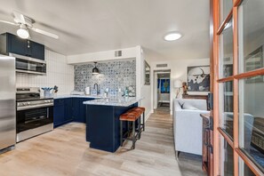 A modern kitchen with a central island, dark blue cabinets, and a patterned backsplash.