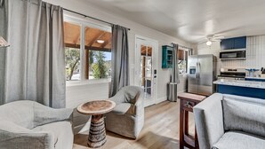 A spacious living area with a large window, a kitchen with modern appliances, and a cozy seating arrangement. - Walk to Shops Restaurants Coffee Live Music (Cave Creek)