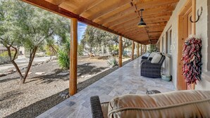 A covered patio with outdoor seating, wooden beams, and a view of trees and a garden. - Walk to Shops Restaurants Coffee Live Music (Cave Creek)