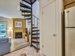 A living room with a spiral staircase, a fireplace, a television, and a sofa. - Coastal 2BR Condo w/ Pool Access | 2 Blks to Beach (Bethany Beach)